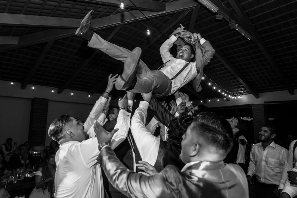 Groom crowd surfs on the dance floor during his wedding reception