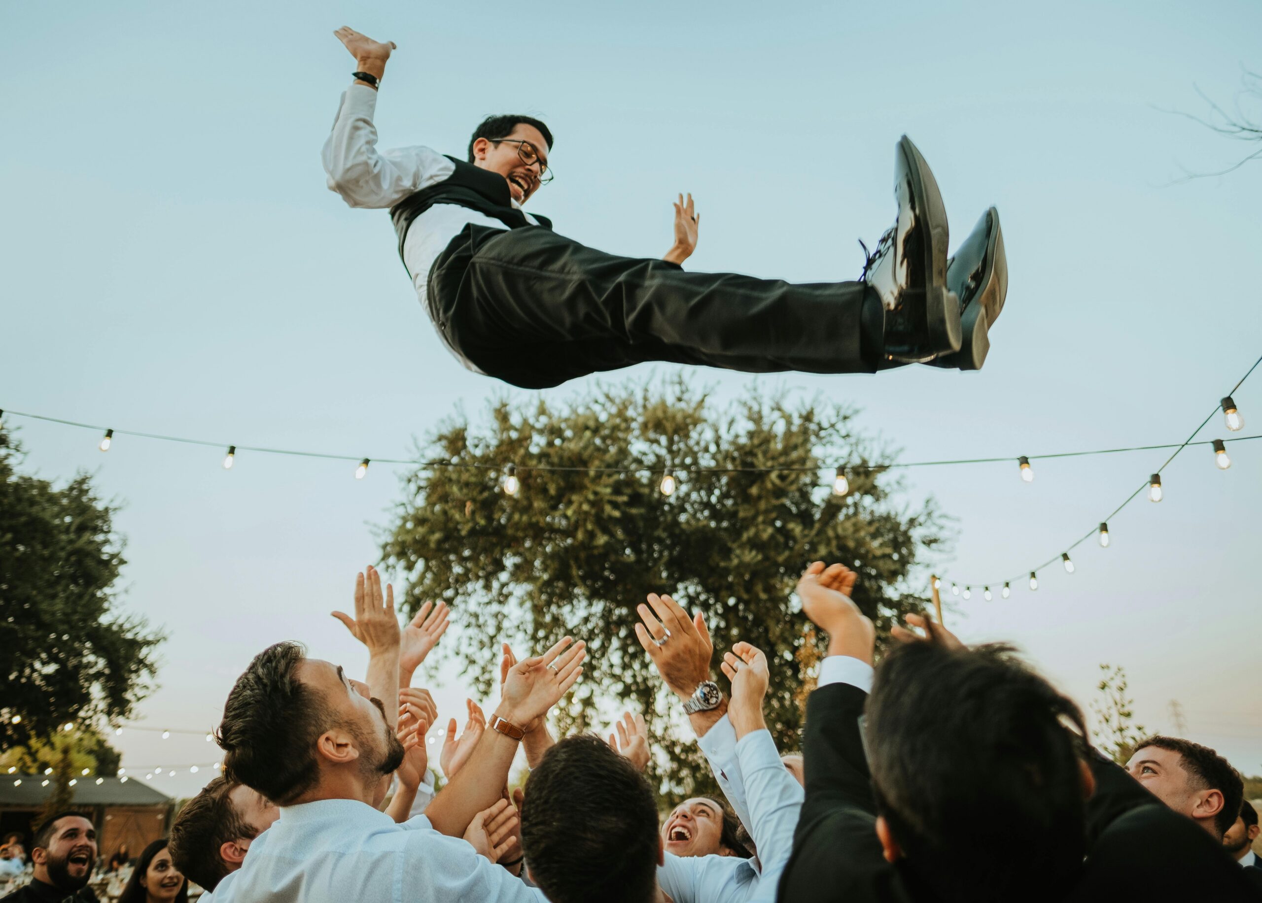 Groom being thrown in the air by groomsmen on the wedding dance floor